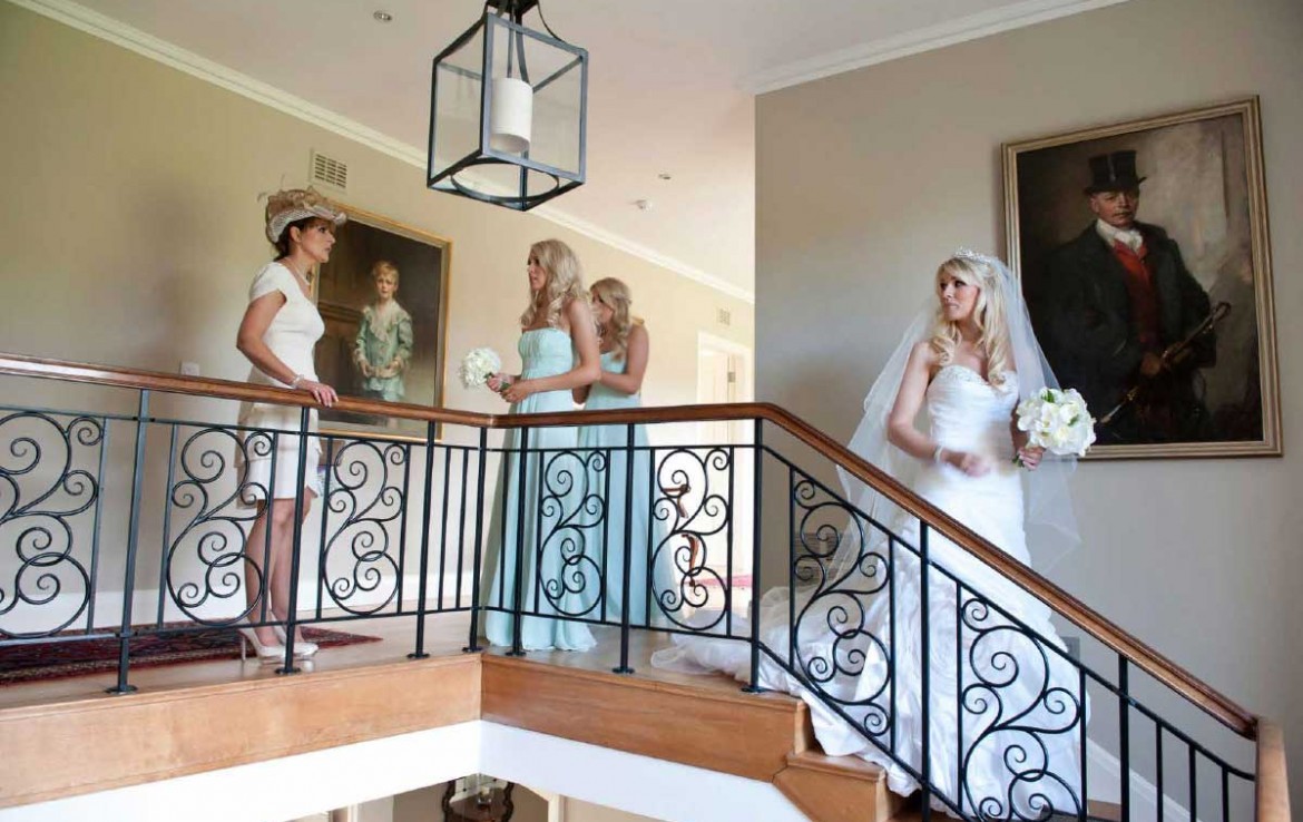 Wedding party in Dunglass Estate with bride descending stairs and bridesmaids behind